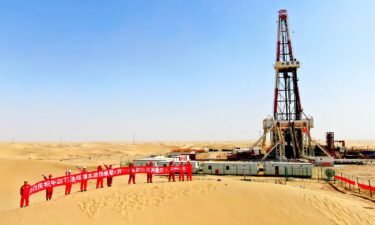 Oil workers hold a banner at Tarim Oilfield at Taklimakan Desert in Shaya County on March 9