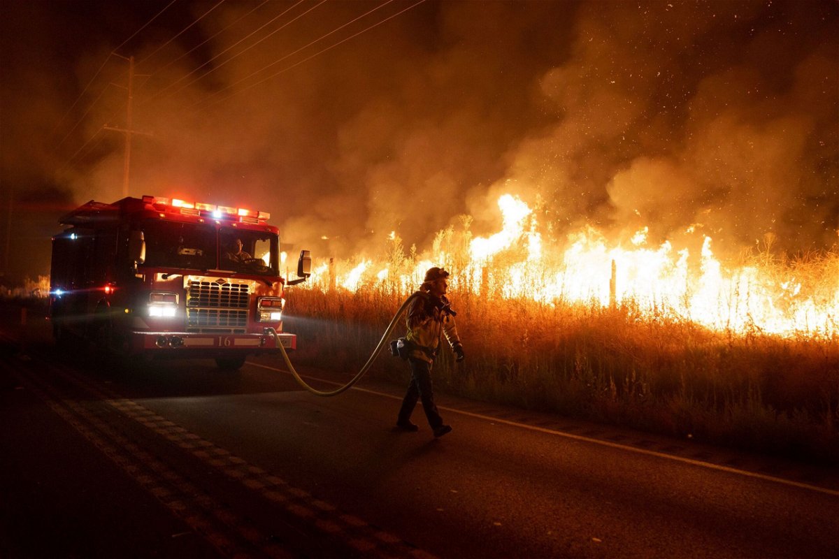 <i>Eric Thayer/AP</i><br/>A firefighter watches flames from the Rabbit Fire approach Gilman Springs Road late Friday