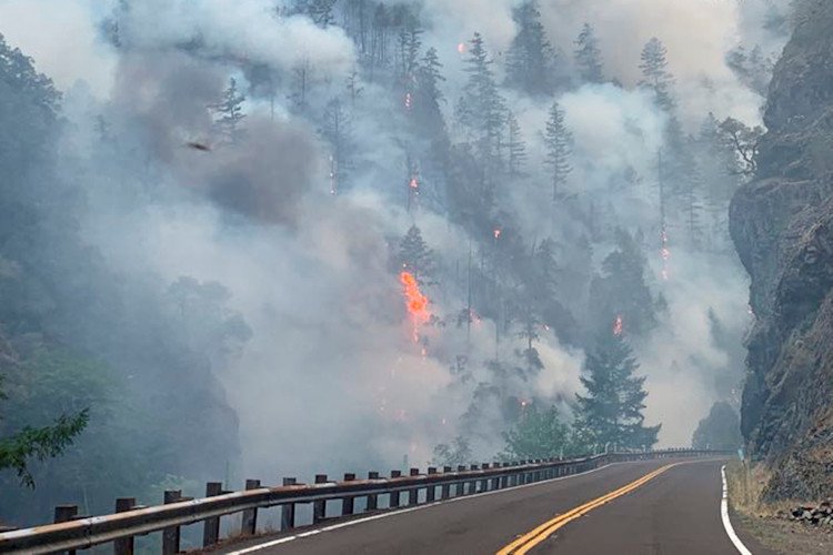 In this photo provided by Caltrans, smoke and flames rise from the Smith River Complex Fire next to the closed U.S. Route 199 in Gasquet, Calif., on Wednesday