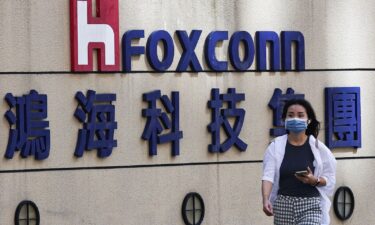 A woman walks past the logo of Foxconn outside the company's building in Taipei