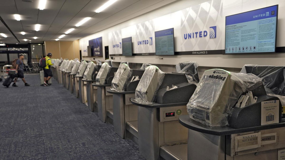 <i>Chris O'Meara/AP</i><br/>United Airlines workers walk past covered kiosks at the Tampa International Airport Tuesday