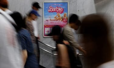 People walk past a promotional poster of film "Barbie" in Tokyo