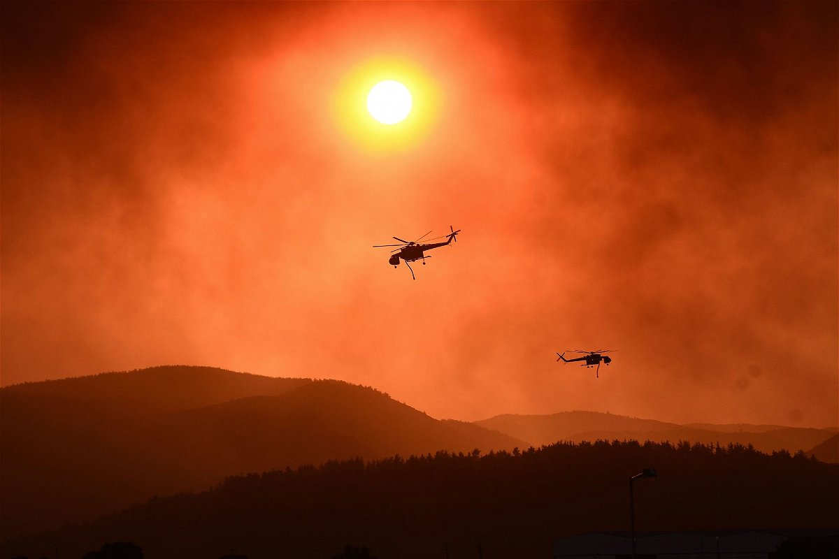 <i>Sakis Mitrolidis/AFP/Getty Images</i><br/>Helicopters fly over as wildfire rages near Alexandroupoli