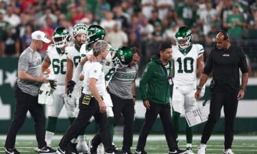 Aaron Rodgers is helped off the field by team trainers after an injury during the first quarter of the New York Jets' game against the Buffalo Bills.