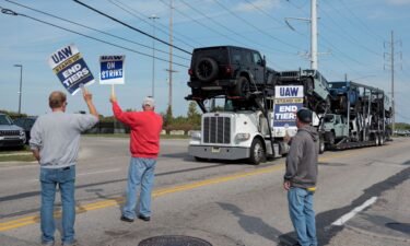 A car hauler transporting Jeep Wranglers drives past striking United Auto Workers members outside the Stellantis Jeep Plant in Toledo