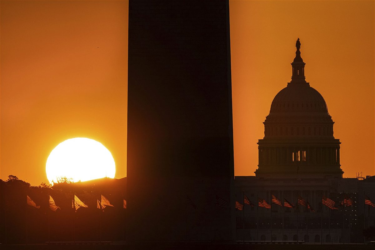 <i>J. David Ake/AP</i><br/>Sunrise behind the Washington Monument and the U.S. Capitol Building illuminates the U.S. flags on the National Mall early Saturday morning