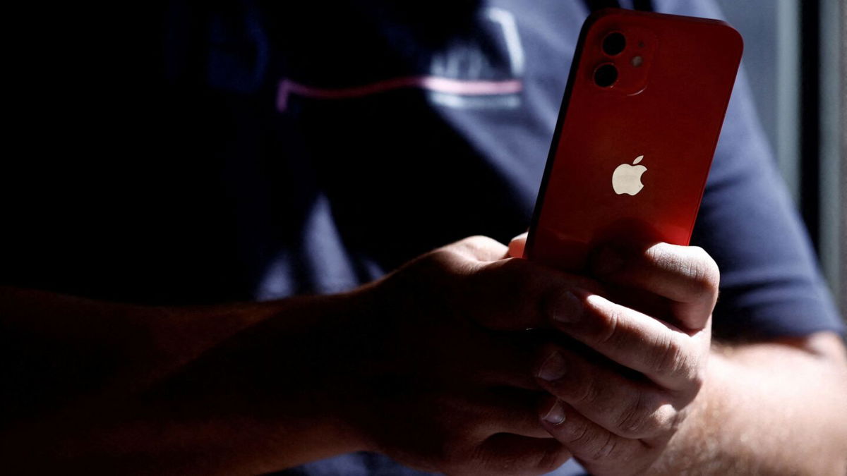 <i>Stephane Mahe/Reuters</i><br/>A man poses with an Apple iPhone 12 in a mobile phone store in Nantes