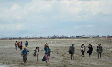 Attendees walk through a muddy desert plain on Saturday at the Burning Man festival site.
