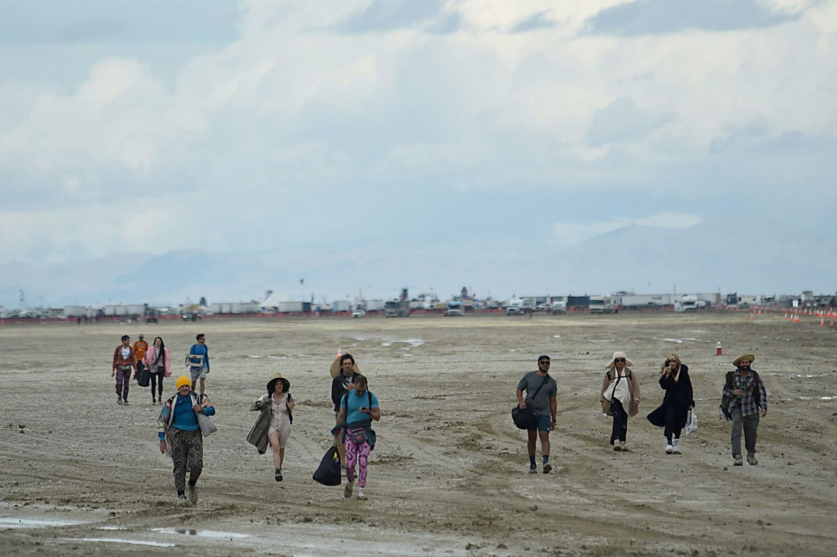 <i>Julie JAMMOT/AFP/Getty Images</i><br/>Attendees walk through a muddy desert plain on Saturday at the Burning Man festival site.