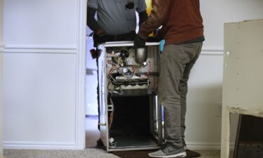 Workers carry a new Carrier natural gas furnace to install at a residential home in Spanish Fork