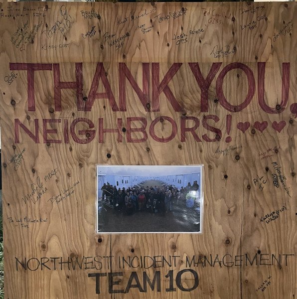 Members of NW Incident Management Team 10 posed for group photo, signed thank-you board at Lookout Fire camp