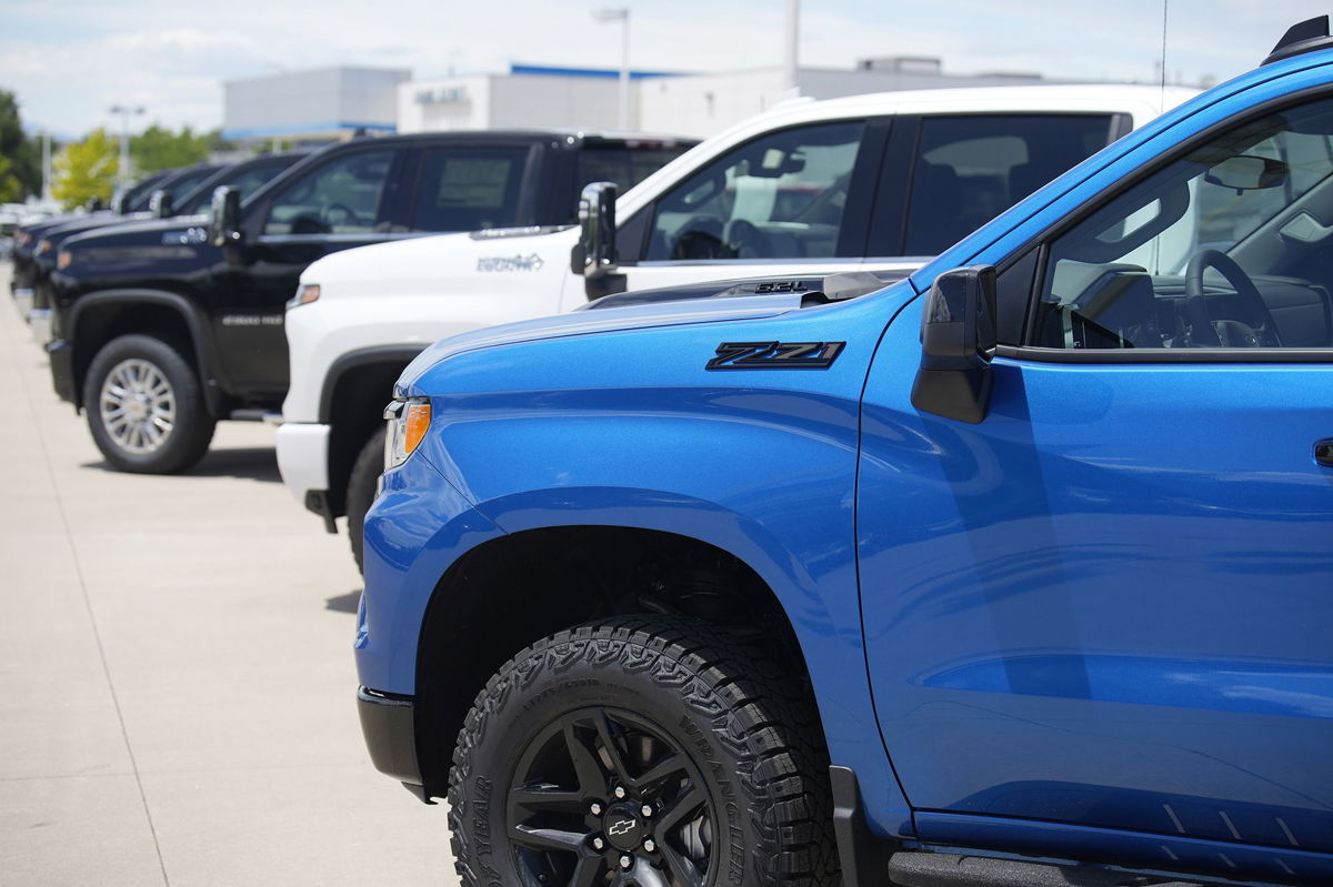 <i>David Zalubowski/AP</i><br/>Unsold 2023 Silverado pickup trucks sit in a long row at a Chevrolet dealership Sunday