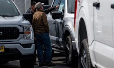 A customer and salesman look at a vehicle for sale at a Ford dealership in Richmond