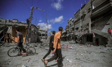 People walk amid the destruction of houses and streets in Khan Younis