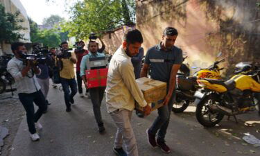 Security officers carry boxes of material confiscated after a raid on NewsClick in New Delhi