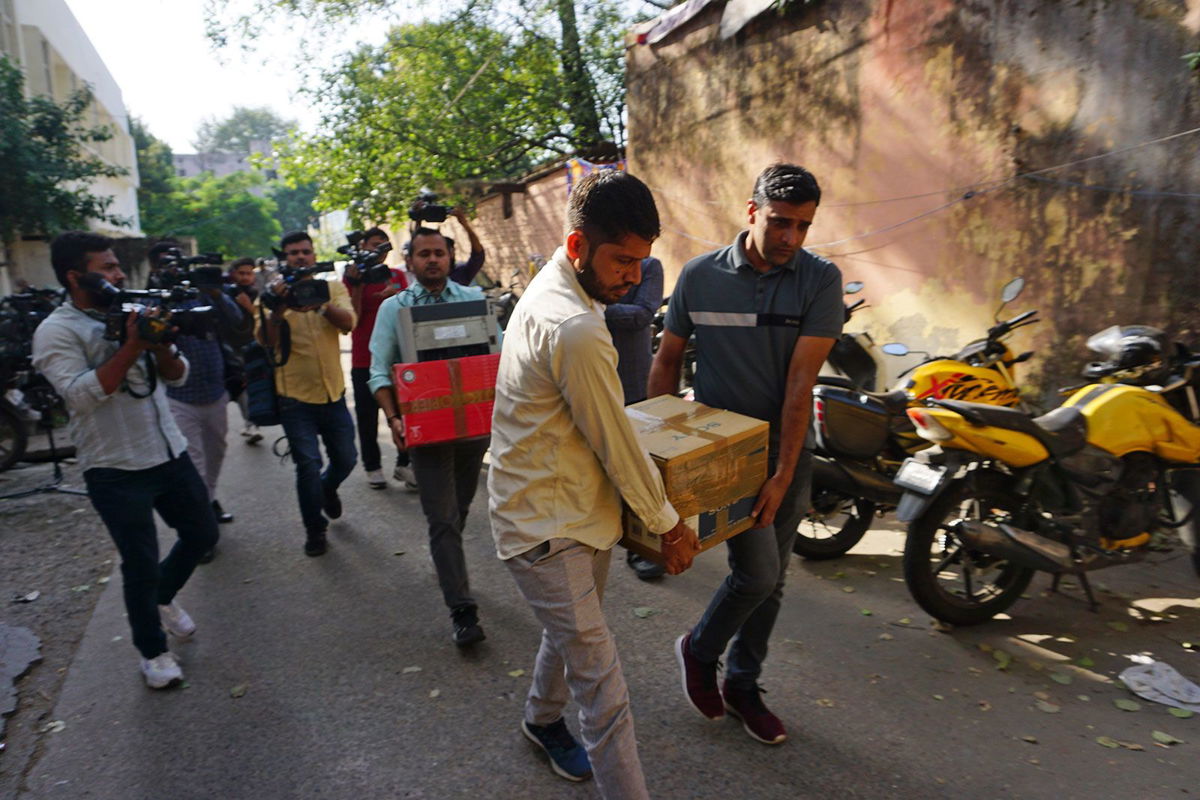 <i>Dinesh Joshi/AP</i><br/>Security officers carry boxes of material confiscated after a raid on NewsClick in New Delhi
