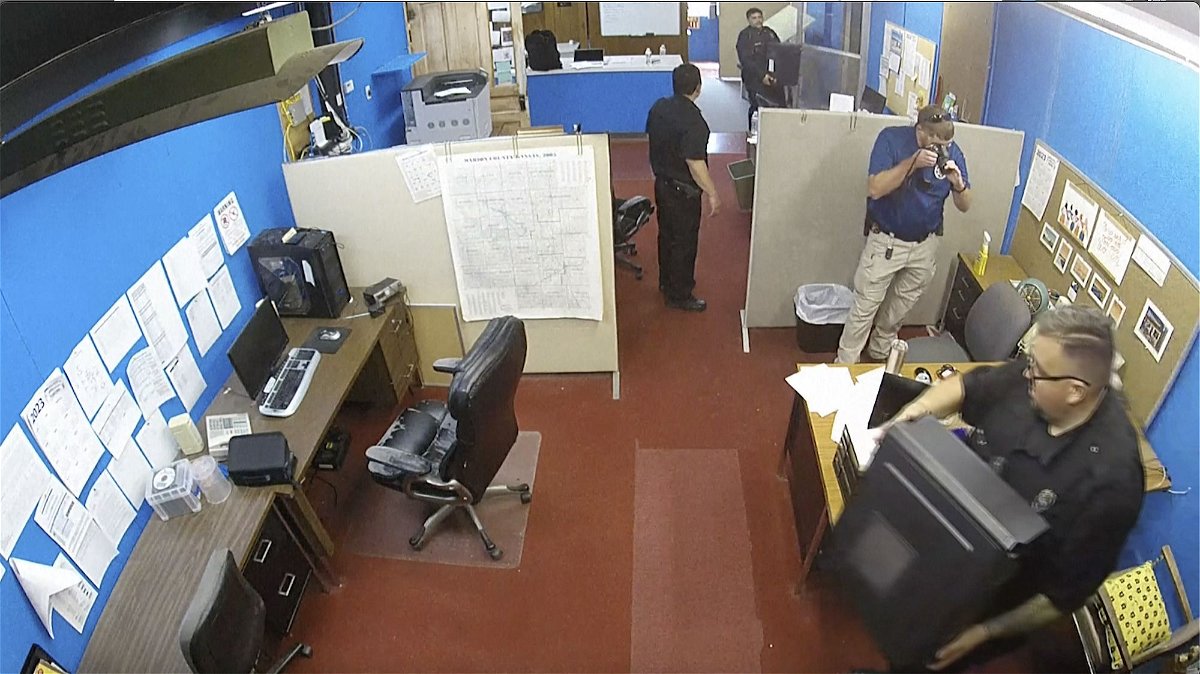 <i>Marion County Record/AP</i><br/>A surveillance image provided by the Marion County Record shows officers confiscating computers and cellphones from the newspaper on August 11.