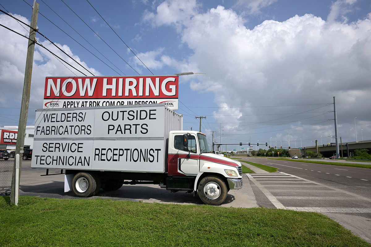<i>Phelan M. Ebenhack/AP</i><br/>A Now Hiring sign advertising job openings is viewed outside a Truck dealership