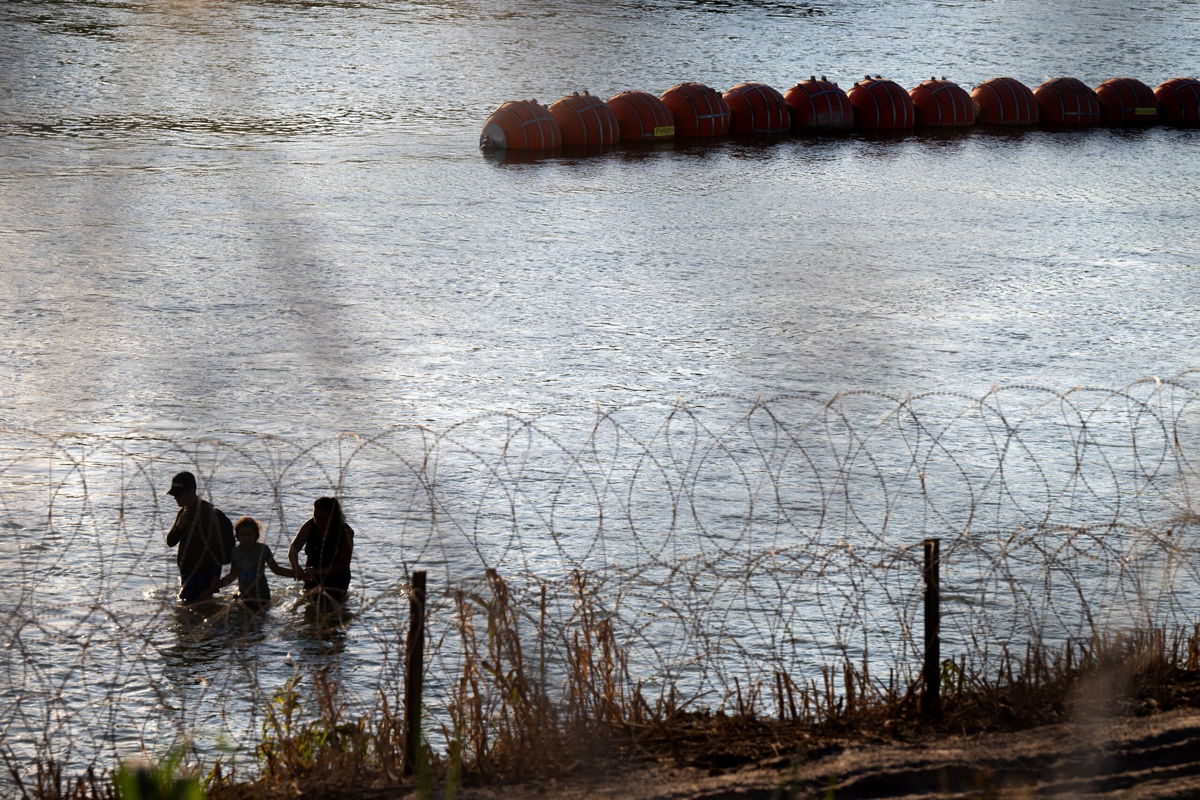 <i>Brandon Bell/Getty Images</i><br/>Migrants cross the Rio Grande river near the buoy barriers on September 11