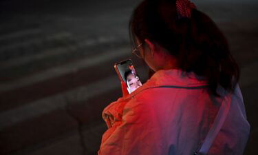 A woman makes a video call with a friend as she waits at an intersection to cross during rush hour on November 15 in Beijing