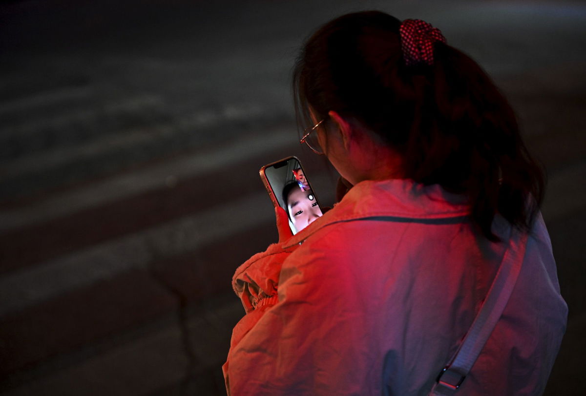 <i>Kevin Frayer/Getty Images</i><br/>A woman makes a video call with a friend as she waits at an intersection to cross during rush hour on November 15 in Beijing