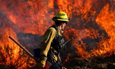 A firefighter works to extinguish the Highland Fire