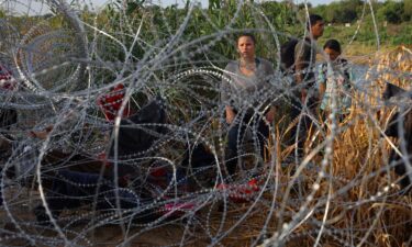 Migrants from Venezuela stand behind concertina wire after crossing the Rio Grande into the United States in Eagle Pass
