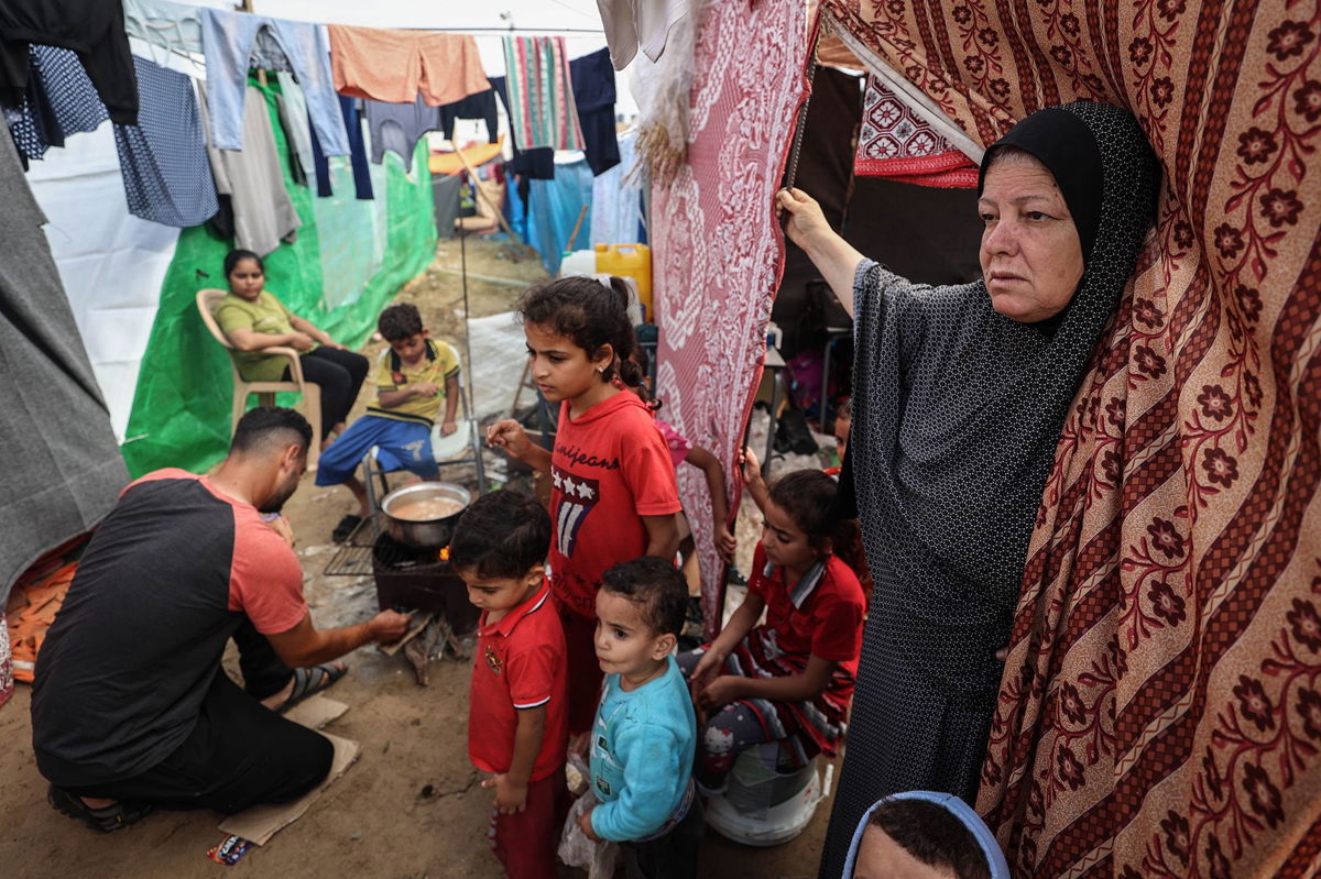<i>Loay Ayyoub for The Washington Post/Getty Images</i><br/>A displaced Palestinian elderly woman stands at the door of her tent with her grandchildren next to her