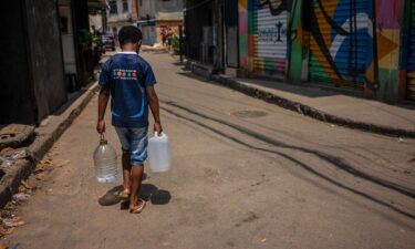 A resident of Rocinha carrying water collected from a natural spring during a heat wave in Rio de Janeiro