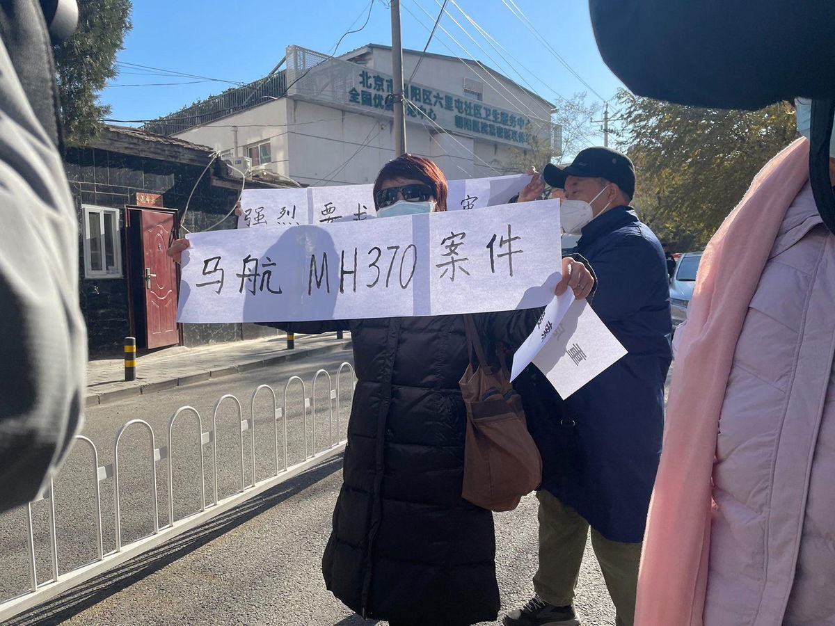 <i>CNN</i><br/>Family members of passengers on board flight MH370 hold up signs demanding an open trial near a court in Beijing's Chaoyang district during a closed-door hearing on November 27.