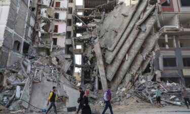 Palestinians walk through damaged buildings in Gaza City.