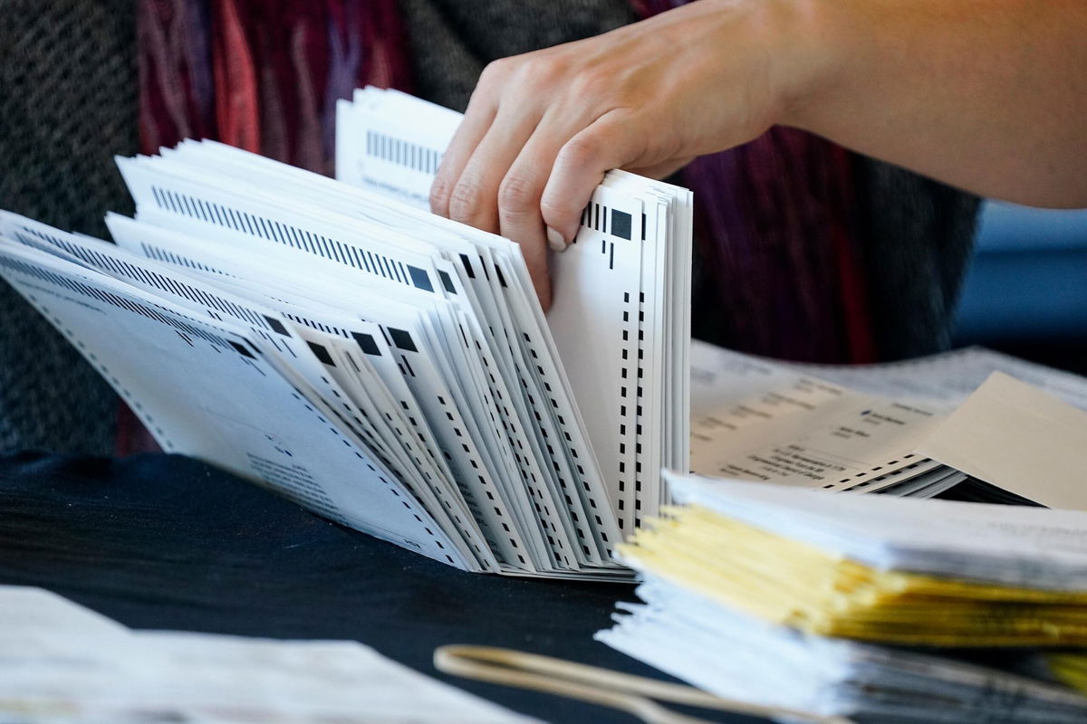 <i>Brynn Anderson/AP</i><br/>An election worker handles ballots as vote counting in the general election continues at State Farm Arena on Thursday