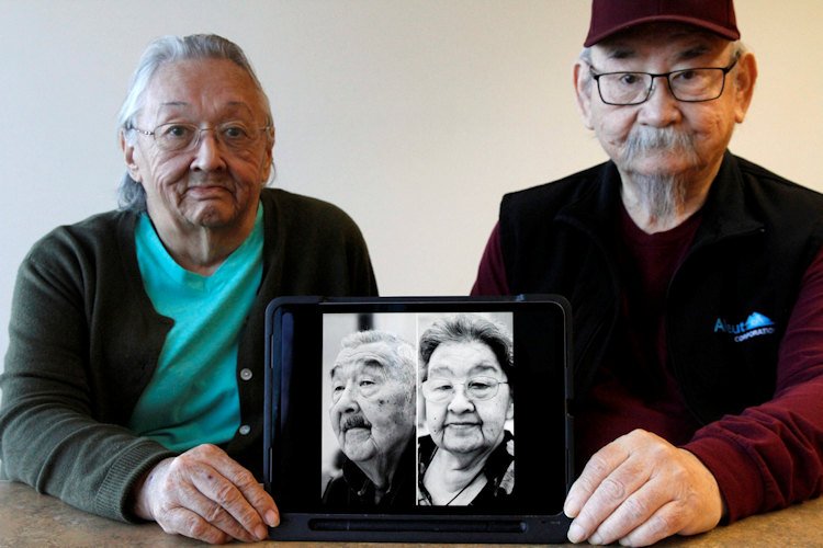 Pauline Golodoff, left, and George Kudrin hold an iPad featuring images of their deceased spouses, Gregory Golodoff and Elizabeth Golodoff Kurdrin, Friday, Dec. 1, 2023, in Anchorage, Alaska. Gregory and Elizabeth were the last two living residents of Attu, Alaska, whose entire population was captured by the Japanese during World War II and sent to Japan until being liberated after the war. The community of Attu was not rebuilt, and residents were resettled elsewhere, mostly in Atka, Alaska.