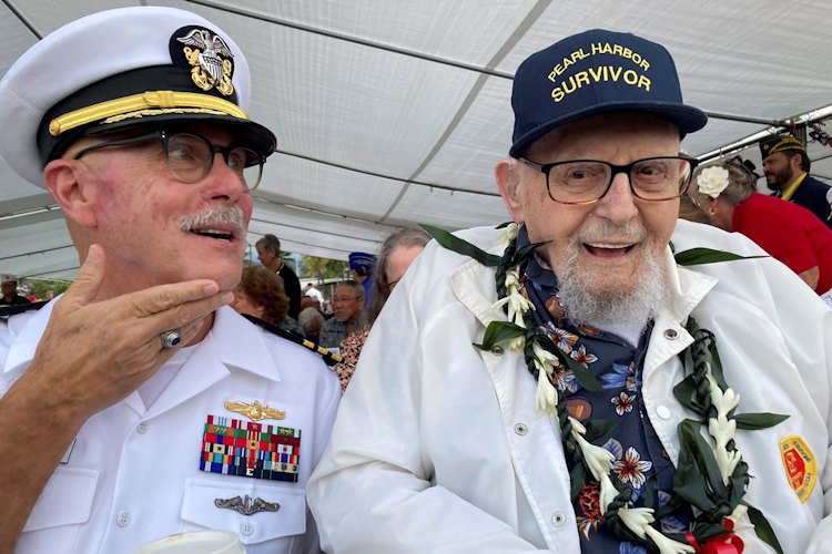 Ira Schab, right, who survived the attack on Pearl Harbor as a sailor on the USS Dobbin, talks with reporters while sitting next to his son, retired Navy Cmdr. Karl Schab, on Dec. 7, 2022, in Pearl Harbor, Hawaii.