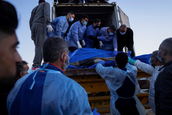 Medics unload the bodies of Palestinians killed in fighting with Israel and turned over by the Israeli military during a mass funeral in Rafah, Gaza Strip, on Tuesday