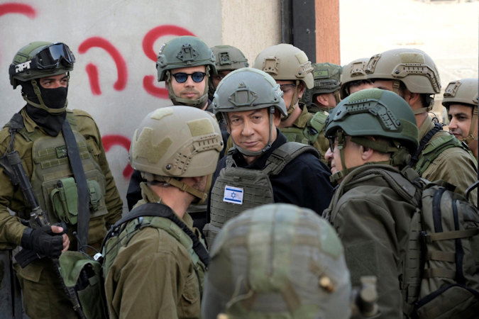 Israeli Prime Minister Benjamin Netanyahu, center, wears a protective vest and helmet as he receives a security briefing with commanders and soldiers in the northern Gaza Strip, on Monday, Dec. 25, 2023.