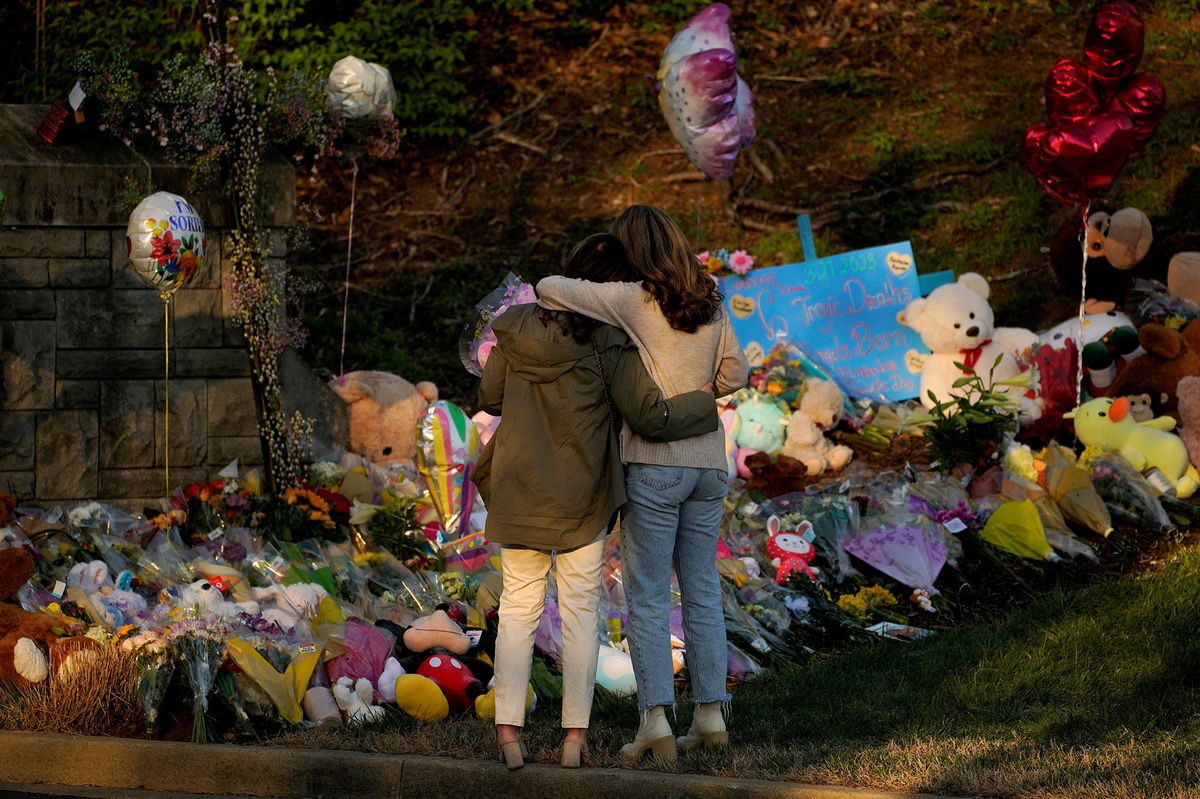 <i>Cheney Orr/Reuters</i><br/>Community members embrace while visiting a memorial at the school entrance after a deadly shooting at the Covenant School in Nashville