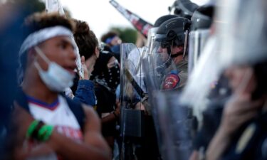 Demonstrators face Austin Police Department officers as they gather in downtown Austin