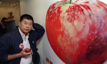 Hong Kong tycoon Jimmy Lai  in 1995 posing in front of a poster advertising his newly launched newspaper Apple Daily.