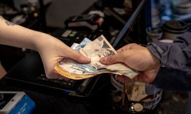 A worker receives Argentine peso banknotes in a shop in Buenos Aires