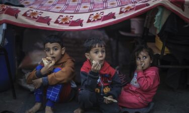 Palestinians displaced by Israeli strikes try to seek cover from rainfall at a UN tent camp in Khan Younis