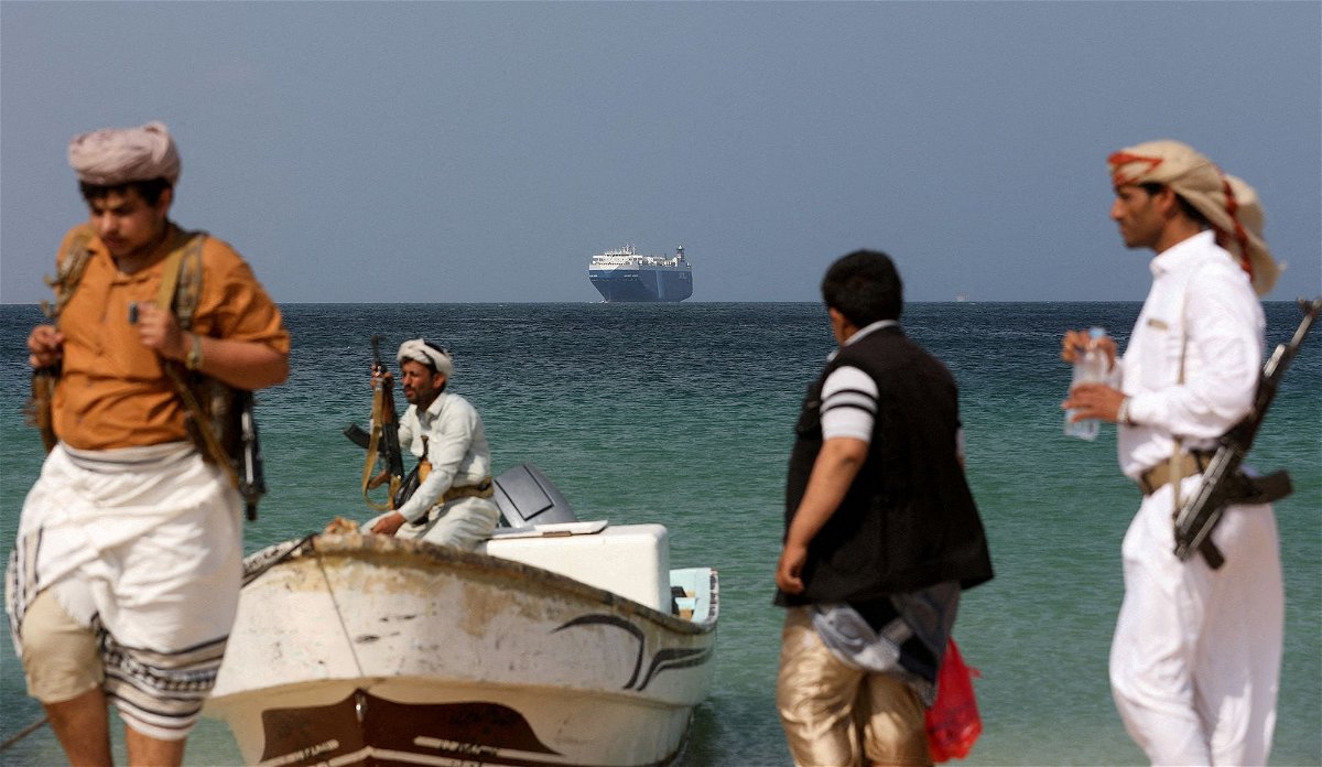 <i>Khaled Abdullah/Reuters</i><br/>Armed men stand on the beach as the Galaxy Leader commercial ship