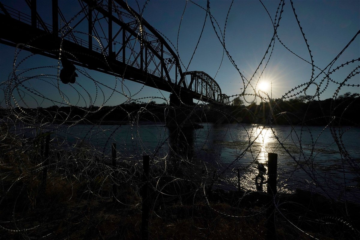 <i>Eric Gay/AP</i><br/>A migrant walks along the banks of the Rio Grande near the Union Pacific International Railroad Bridge in September in Eagle Pass