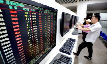 Investors watch computer screens displaying stock price figures at a stock exchange hall on August 28