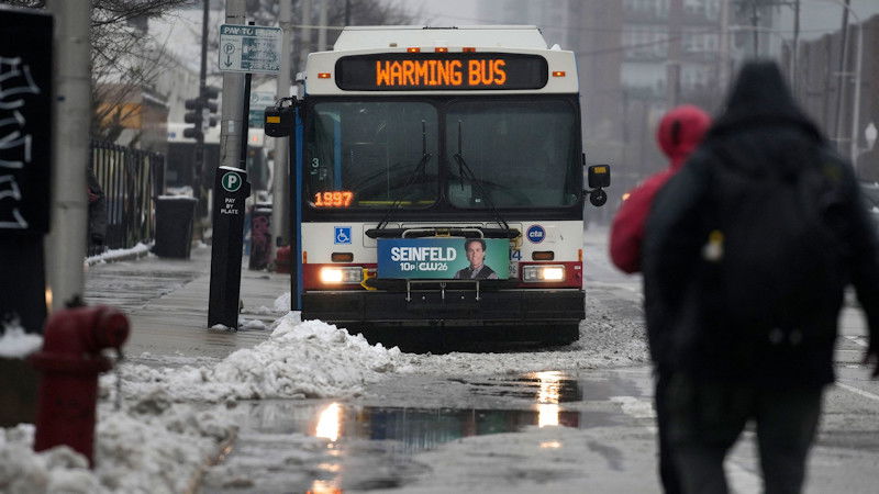 Snow falls Friday as migrants stay warm in city buses in Chicago.