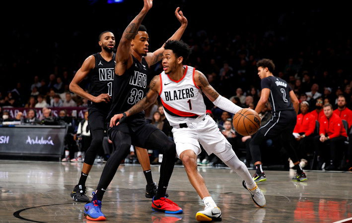 ortland Trail Blazers guard Anfernee Simons, front right, drives the baseline against Brooklyn Nets center Nic Claxton (33) and forward Mikal Bridges, left, during the first half of Sunday's game 