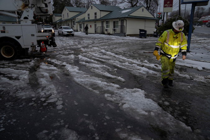 worker with International Line Builders Inc. walks through melting snow and ice as freezing rain falls to help crew members turn the power back on Thursday in Portland
