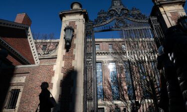 A pedestrian passes a gate to Harvard Yard on Massachusetts Ave. in Cambridge