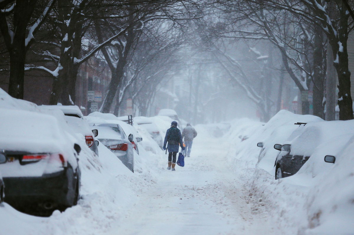 <i>Brian Snyder/Reuters</i><br/>Pedestrians make their way along a snow-covered street during a storm in Cambridge