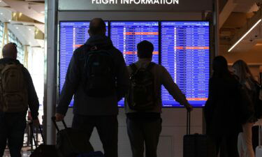 Travelers looks at a flight information board at Ronald Reagan Washington National Airport in 2023.